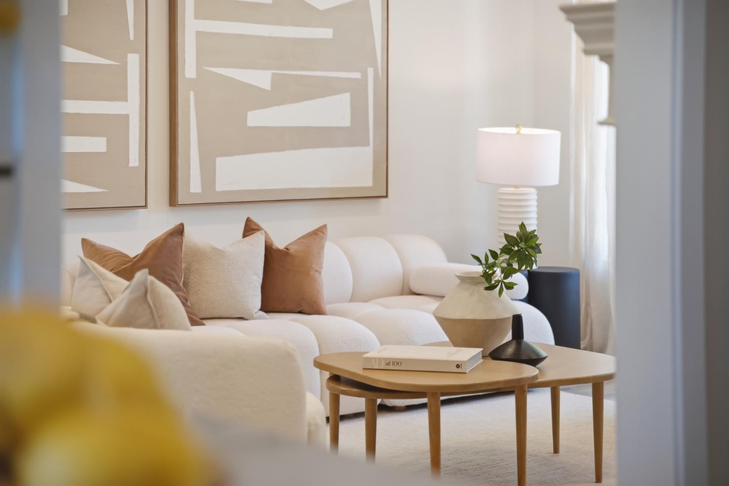 Living room with a curved white sofa, abstract wall art, and a round wooden coffee table.