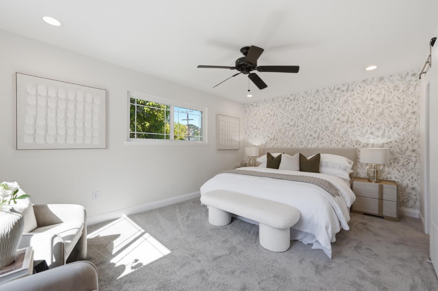 Staged bedroom with a floral accent wall, upholstered bed, and ceiling fan.