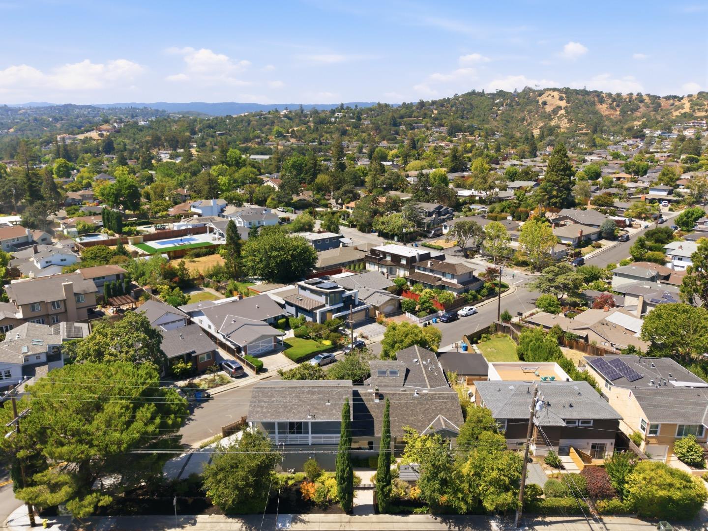 Aerial view of San Carlos homes and tree-lined streets, with rolling hills in the distance.