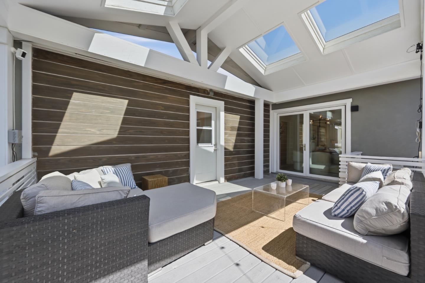 Covered patio with skylights, dark wood siding, and cushioned wicker seating.