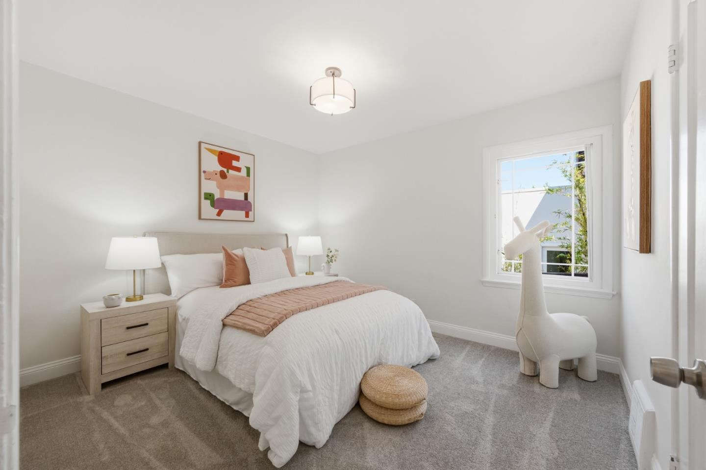 Staged bedroom with a white bed, colorful abstract art, and a sculptural white chair by the window.