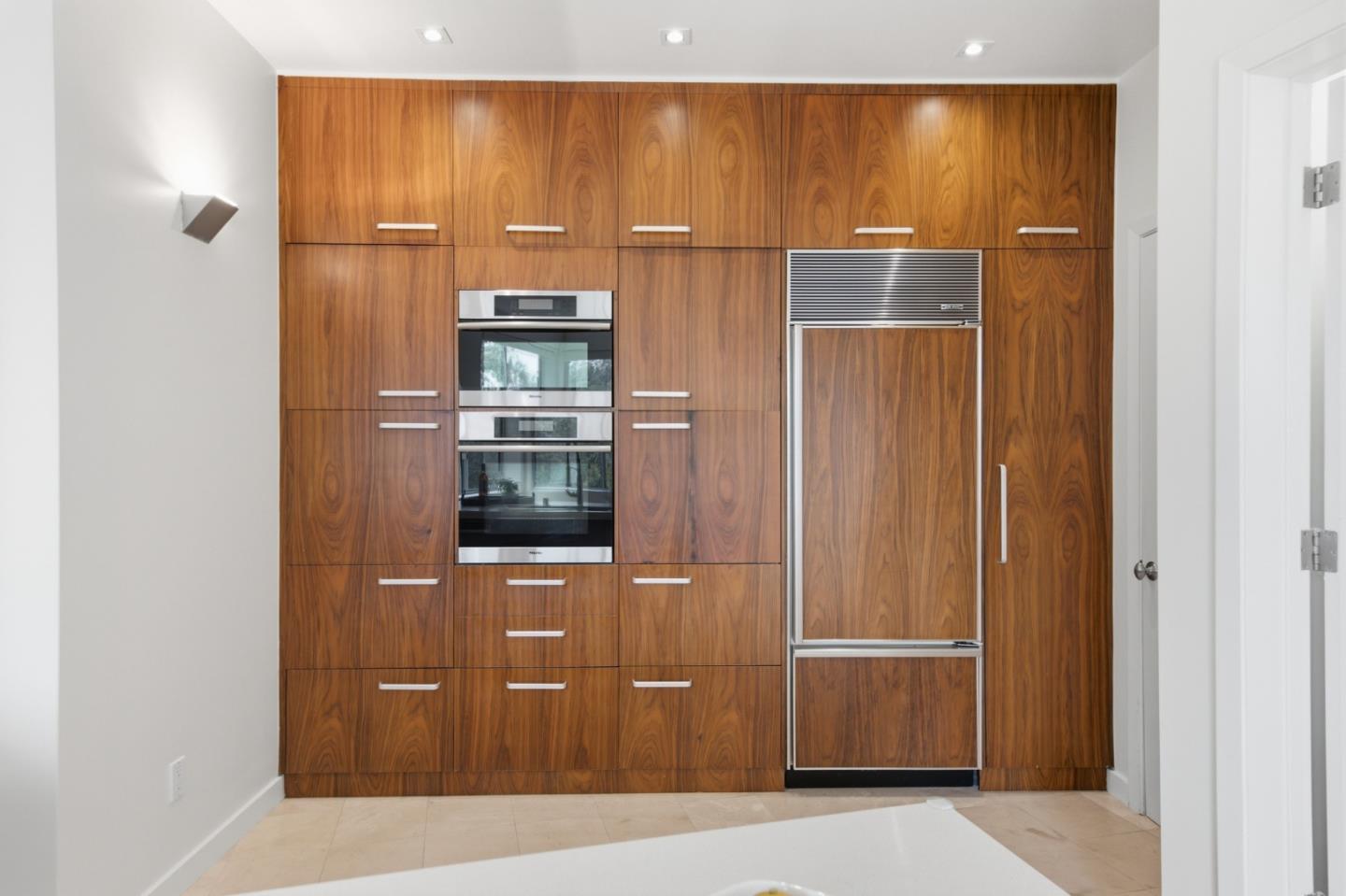 Kitchen with full-height wood cabinetry, a built-in double oven, and an integrated refrigerator.