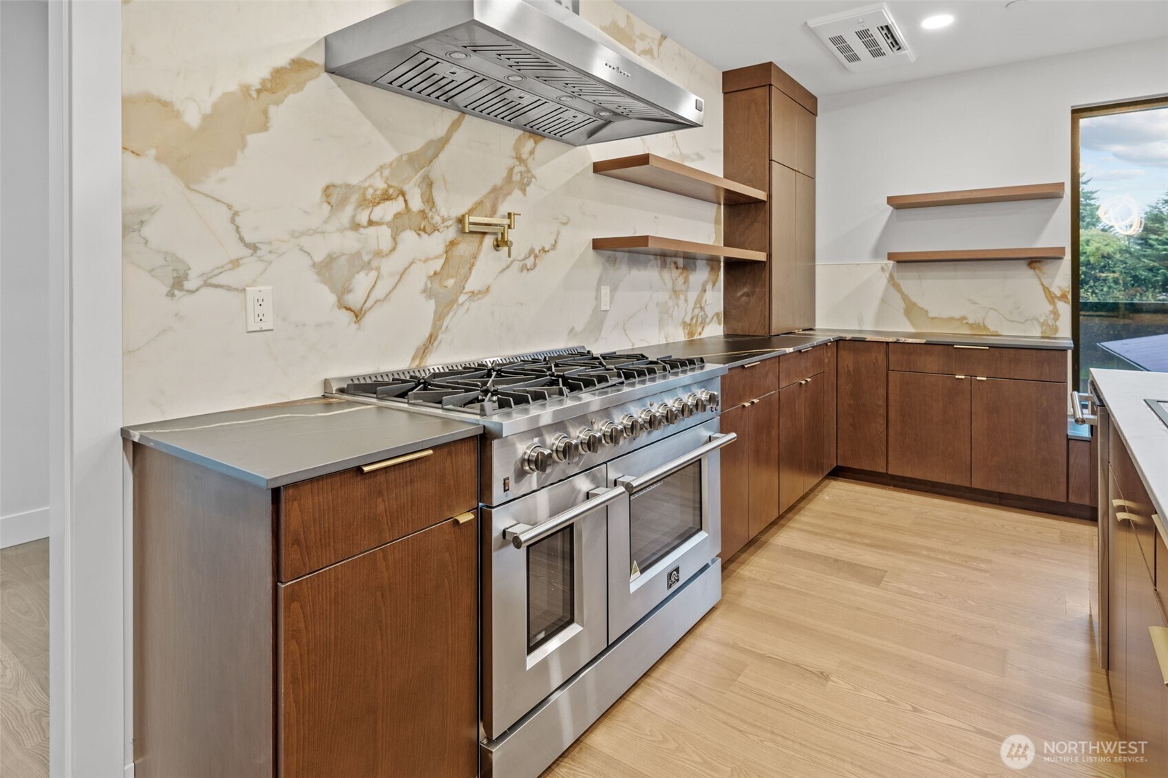Modern kitchen with a stainless steel range, walnut cabinetry, and dramatic veined stone backsplash.