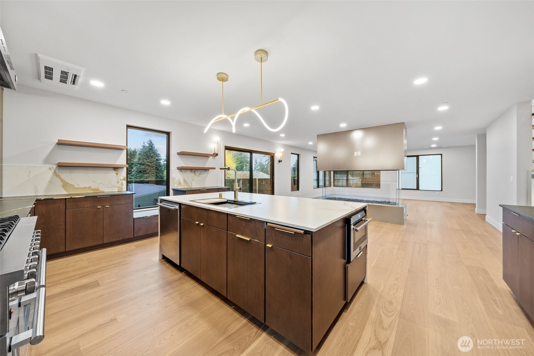 Modern kitchen with a large island, dark wood cabinets, and an open living area.