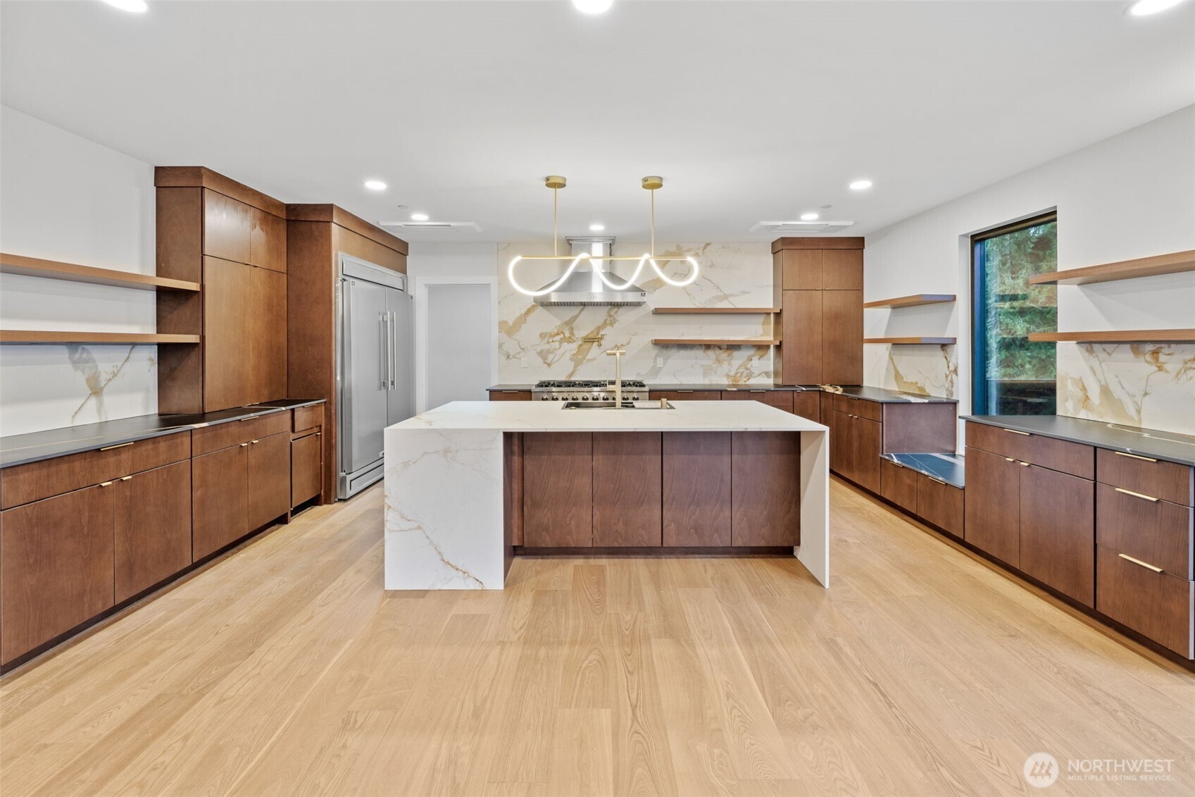 Modern kitchen with walnut cabinetry, a white stone island, and a marble-pattern backsplash.
