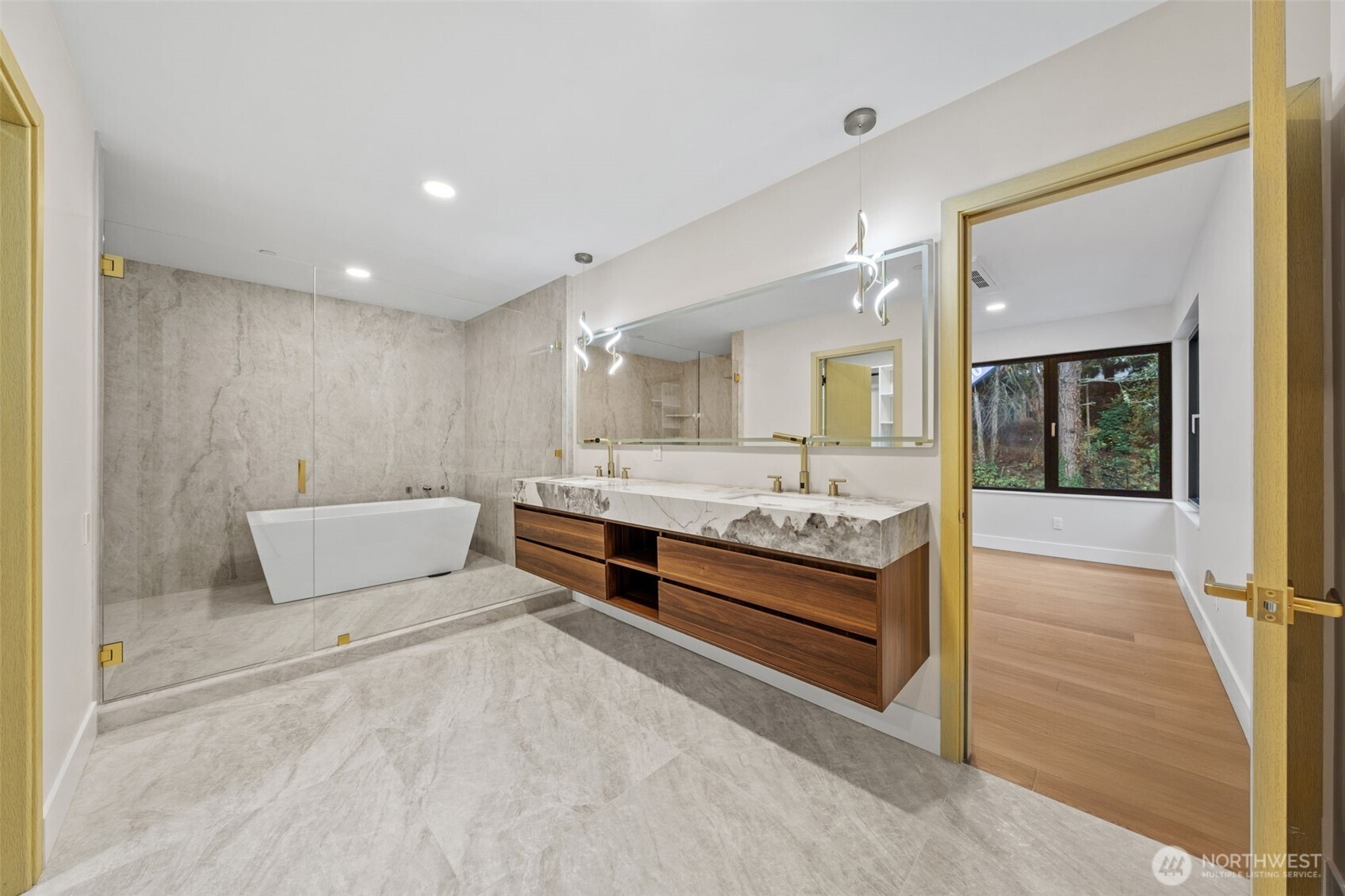 Primary bathroom with a glass-enclosed tub, marble finishes, and a double wood vanity.