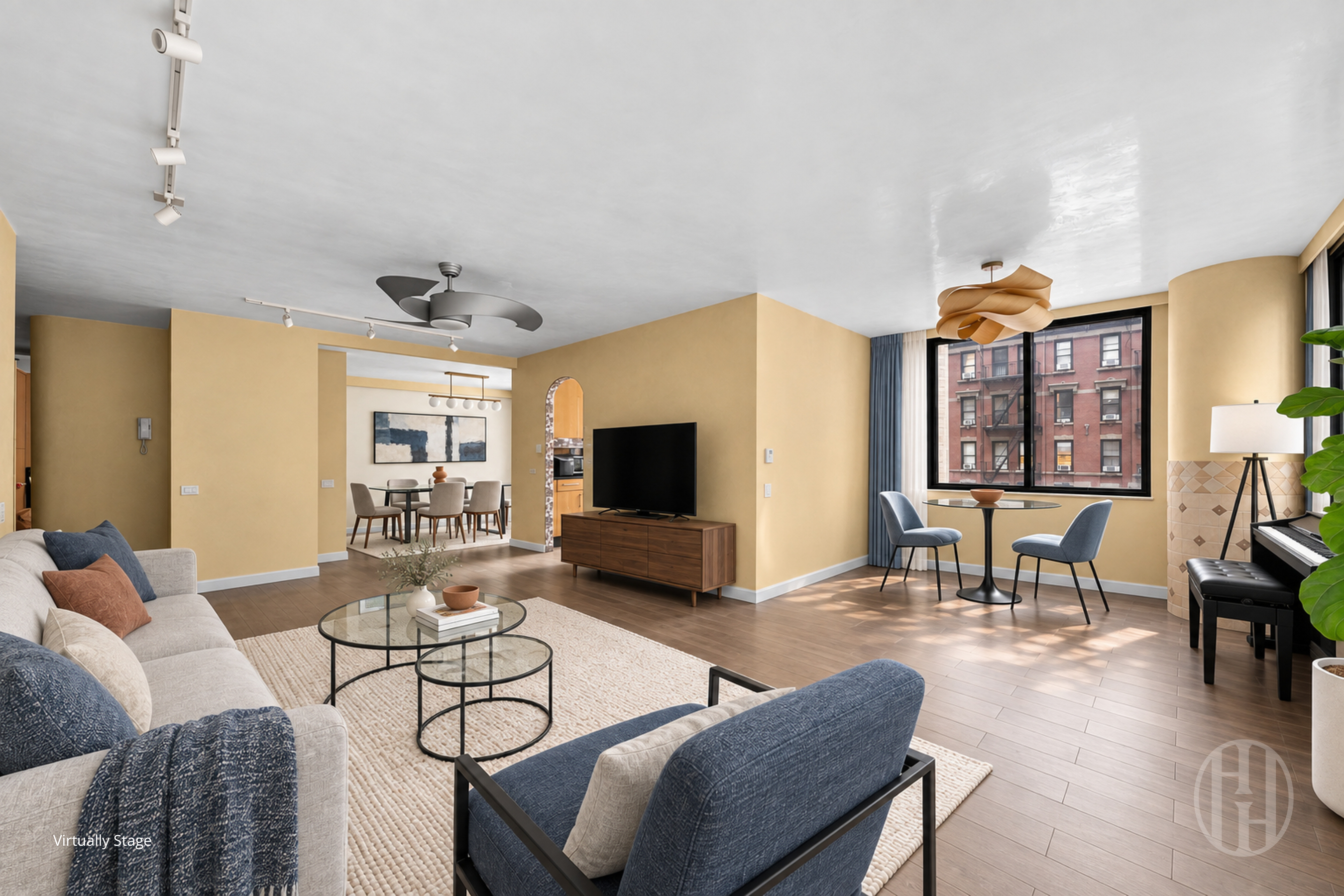 Virtually staged living room with blue accent chairs, a large window, and an adjoining dining area.