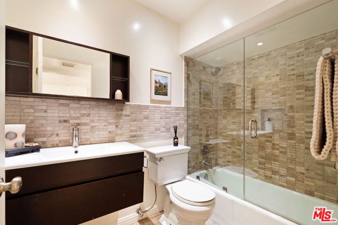 Bathroom with a dark floating vanity and stone-tile tub-shower enclosure.