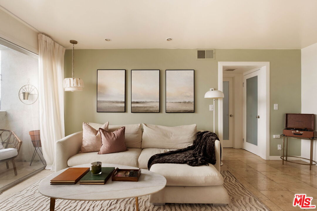 Staged living room with a cream sectional, landscape prints, and a stone coffee table.