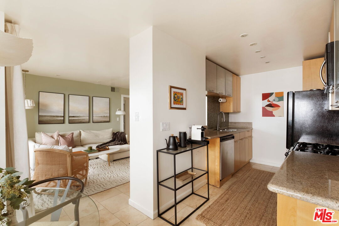 Open-plan condo kitchen and living room with light wood cabinets and a cream sectional.