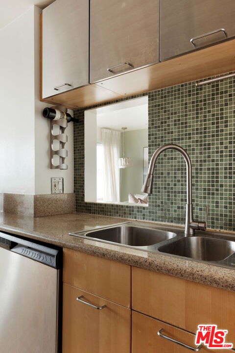 Kitchen with dark green tile backsplash, light wood cabinets, and a double-basin sink.