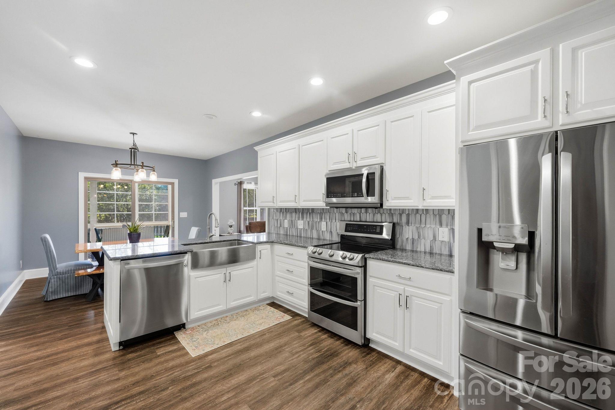 Bright kitchen with white cabinets, stainless-steel appliances, a large island, and an adjoining dining nook.