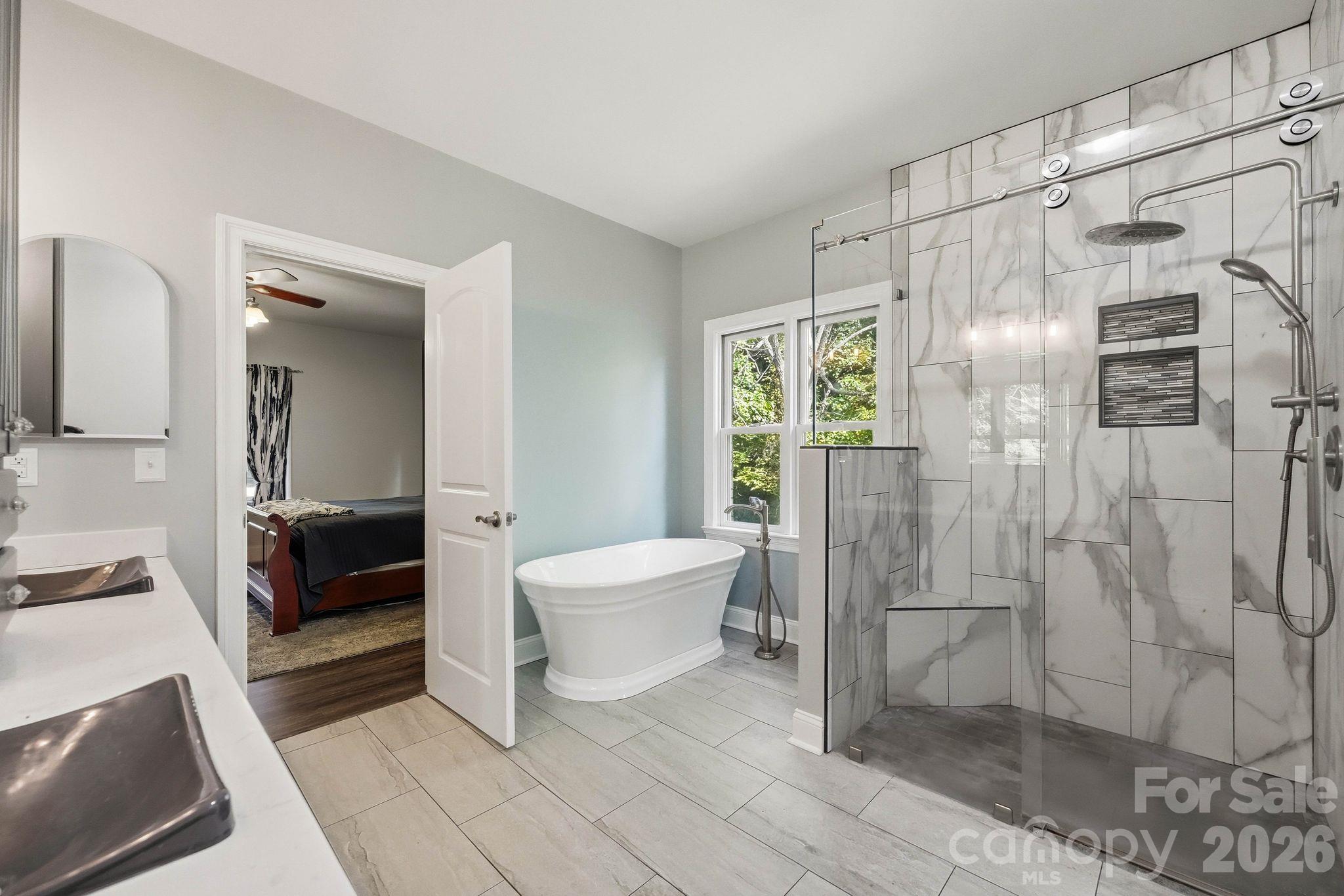 Bathroom with a freestanding soaking tub, marble-look tiled walk-in shower, and double-sink vanity.