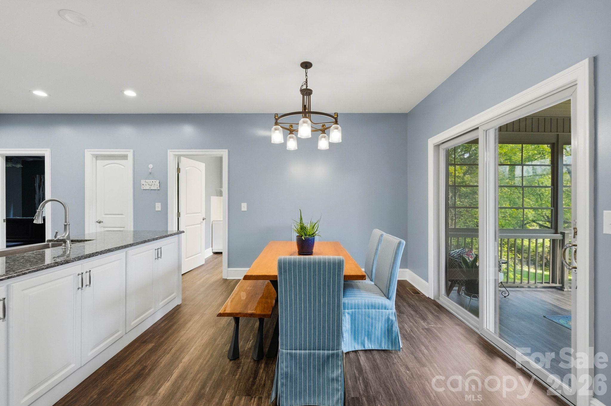 Dining area with a wooden table and blue striped chairs beside sliding doors to a covered porch.