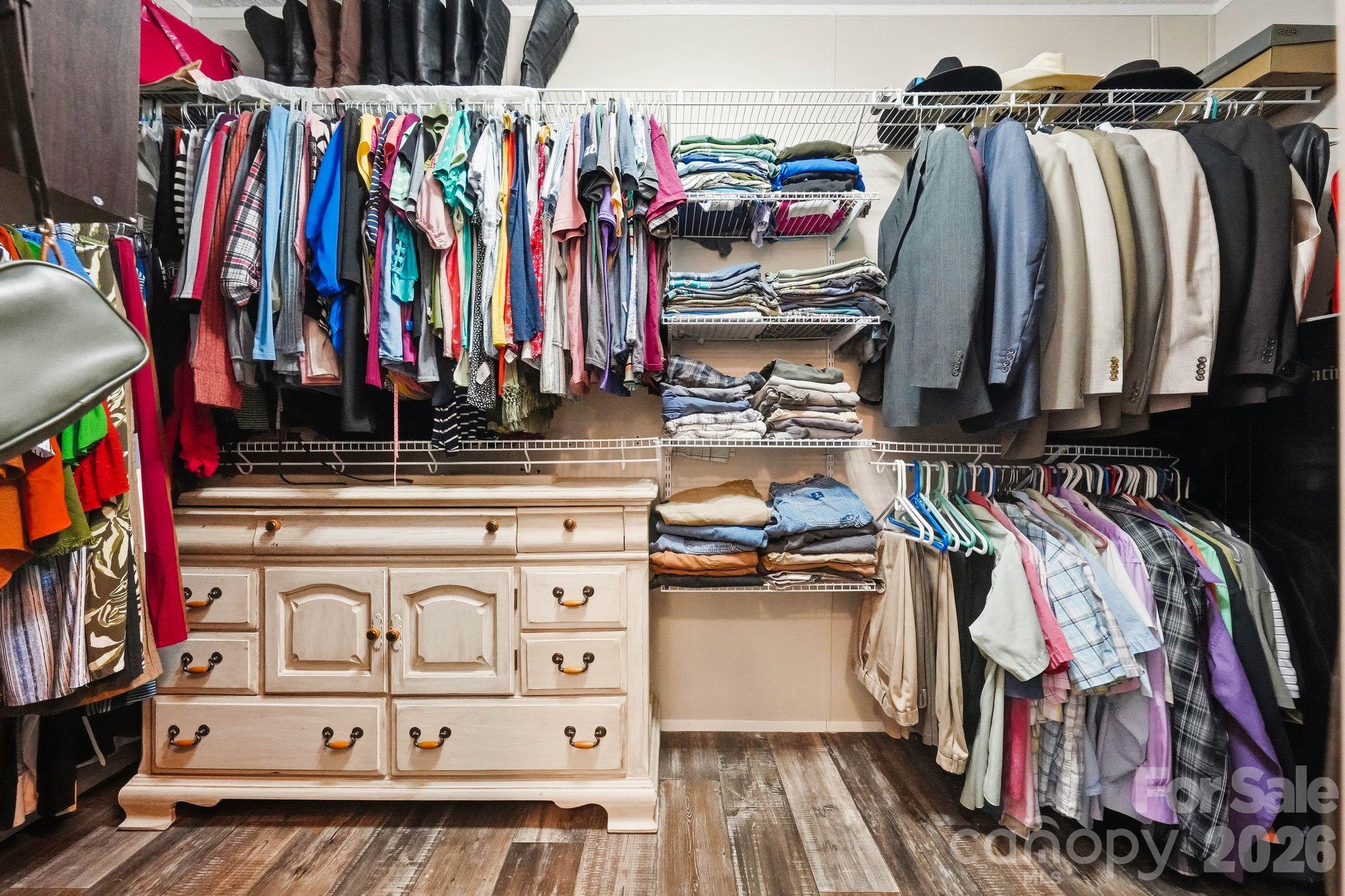 Walk-in closet with extensive clothing storage and a large cream-colored drawer cabinet.