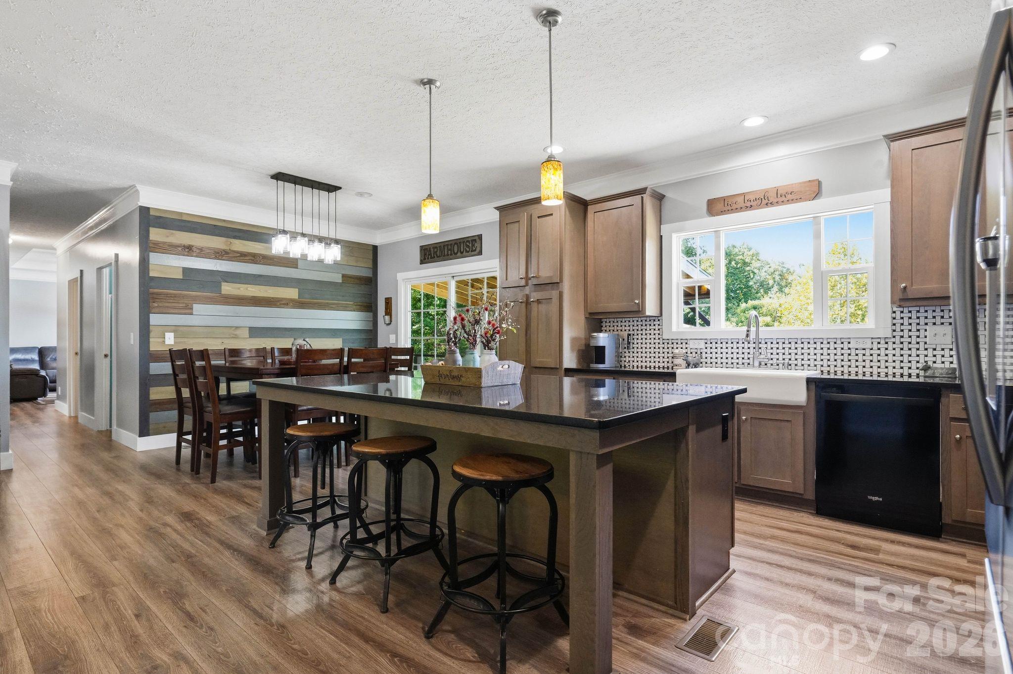Kitchen with a large island, bar stools, farmhouse sink, and multicolored wood accent wall.