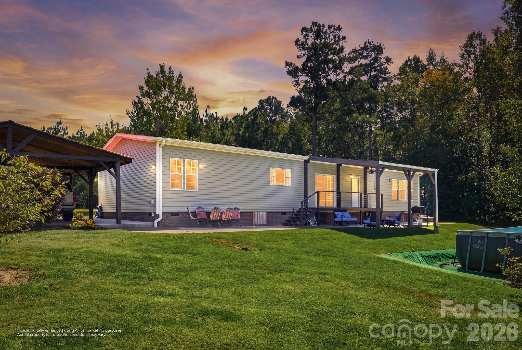 Single-story home at dusk with a covered patio, carport, broad lawn, and above-ground pool.