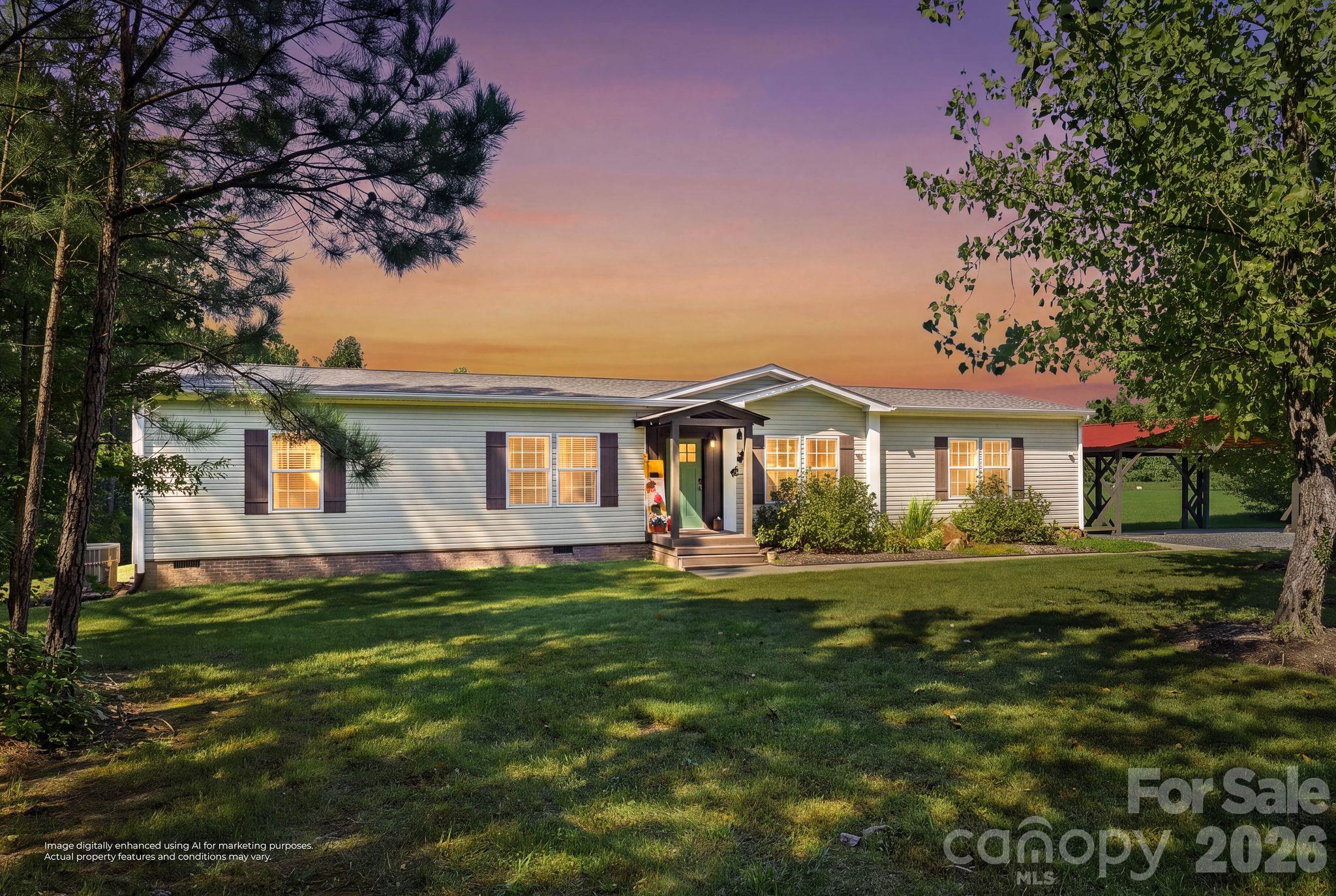 Single-story home with a covered entry and carport, framed by trees above a broad green lawn at sunset.