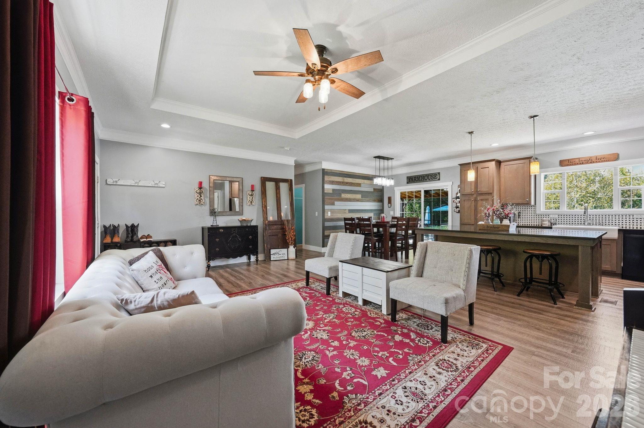 Open-plan living room and kitchen with a red patterned rug, white sectional, and large island.