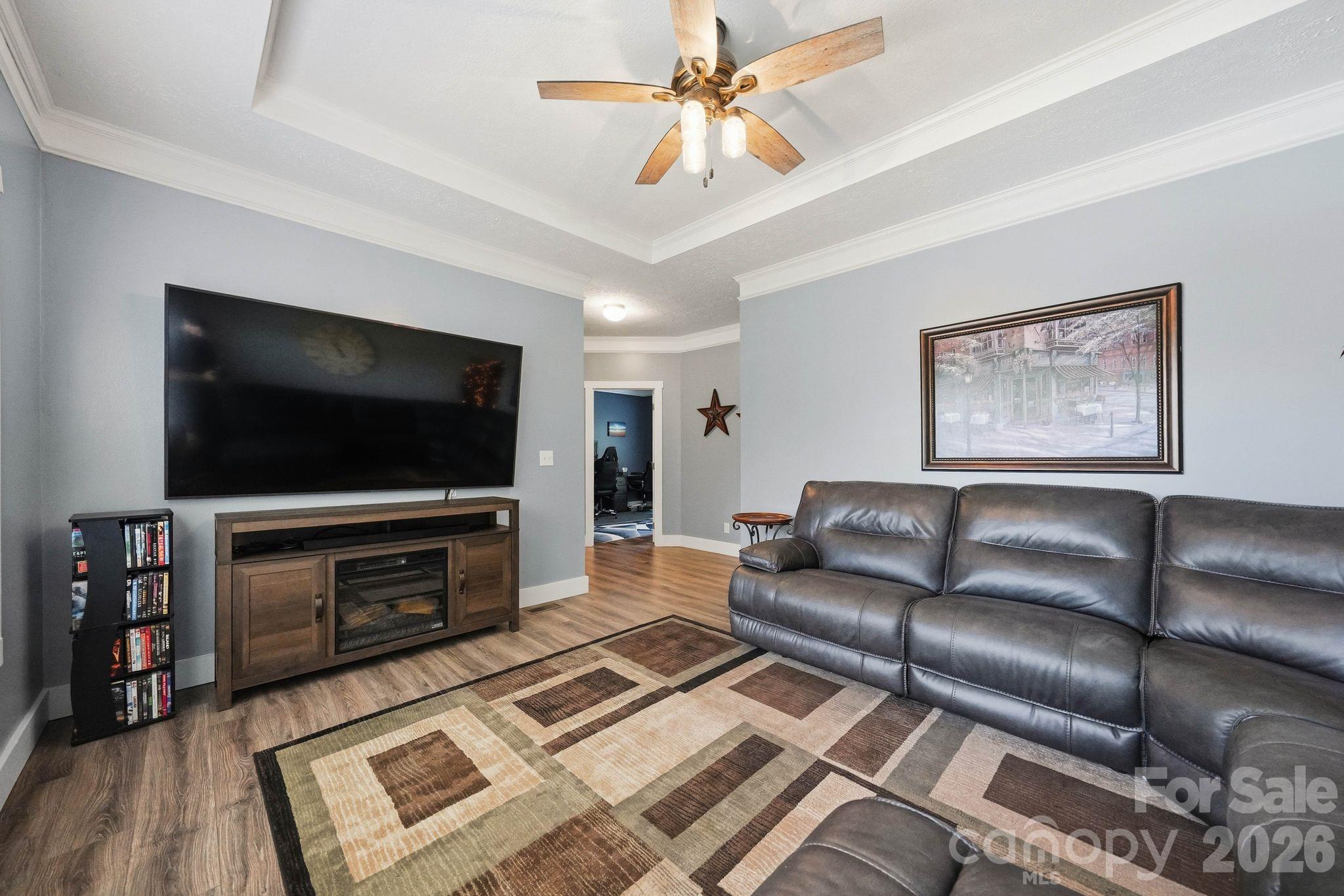 Furnished living room with a gray leather sectional, large television, and geometric area rug.