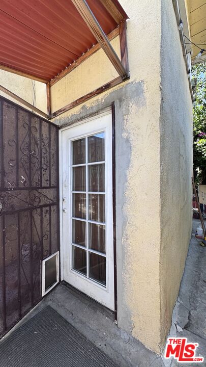 Side entrance at 1065 N Gage Ave with a white-framed glass door, decorative metal security gate, and covered entry.