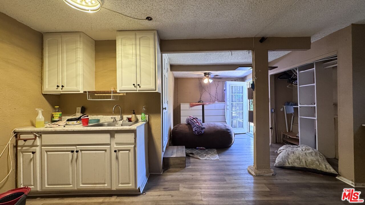 View from the kitchen into the living area at 1065 N Gage Ave, with cream cabinets, wood flooring, a beanbag chair, and built-in shelving.