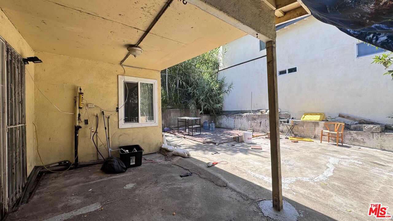 Covered patio and concrete courtyard at 1065 N Gage Ave, with a small window, utility equipment, and outdoor seating.