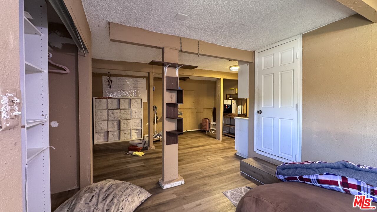 Interior room at 1065 N Gage Ave with wood-look flooring, open closet shelving, a mirrored divider, and a white door.