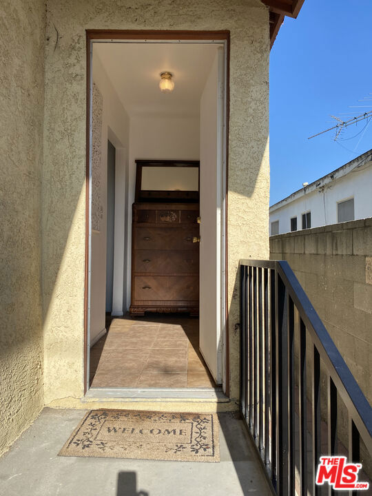 Front entry and narrow balcony at 2643 S Spaulding Avenue, with a welcome mat and a wooden dresser visible inside the open doorway.