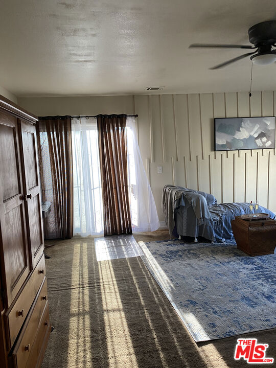 Bedroom at 2643 S Spaulding Avenue with a wooden wardrobe, curtained glass doors, a bed, and sunlight across the carpet.