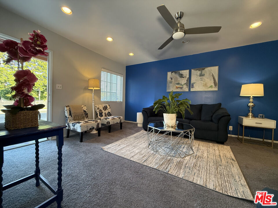 Living room at 2643 S Spaulding Avenue with a dark sofa against a blue accent wall, two patterned armchairs, and a glass coffee table on a neutral rug.