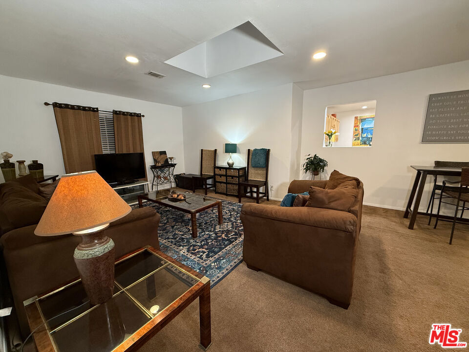Living room at 2643 S Spaulding Avenue with brown sofas, a patterned blue rug, a TV and a small dining area.
