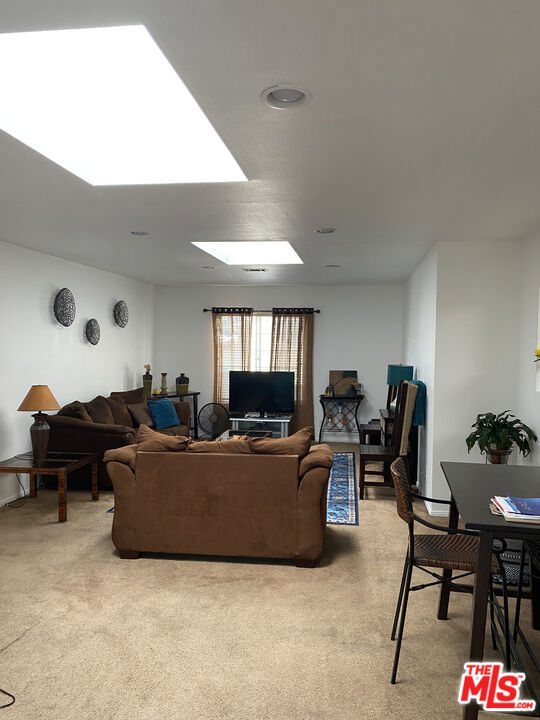 Spacious living room at 2643 S Spaulding Avenue with beige carpet, a brown sofa, television, and dining table.
