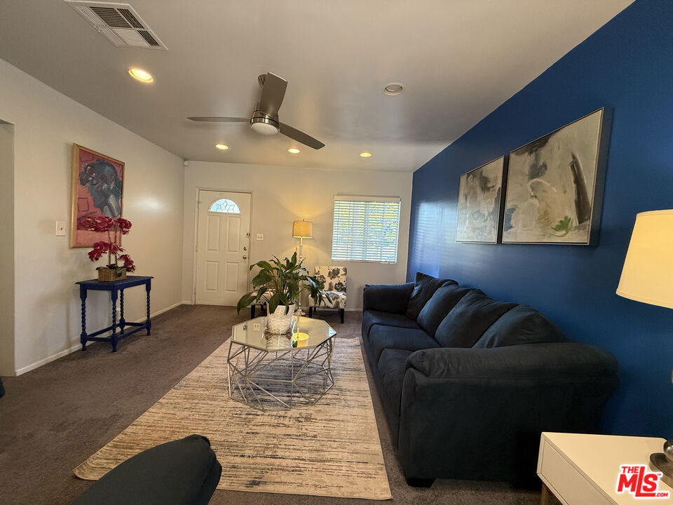 Living room at 2643 S Spaulding Avenue with a navy accent wall, dark sectional sofa, glass coffee table, and entry door.