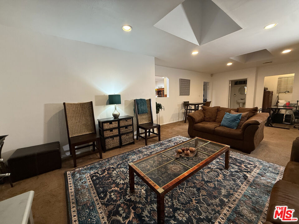 Living room at 2643 S Spaulding Avenue with a brown sofa, patterned area rug, glass-top coffee table, and accent chairs.