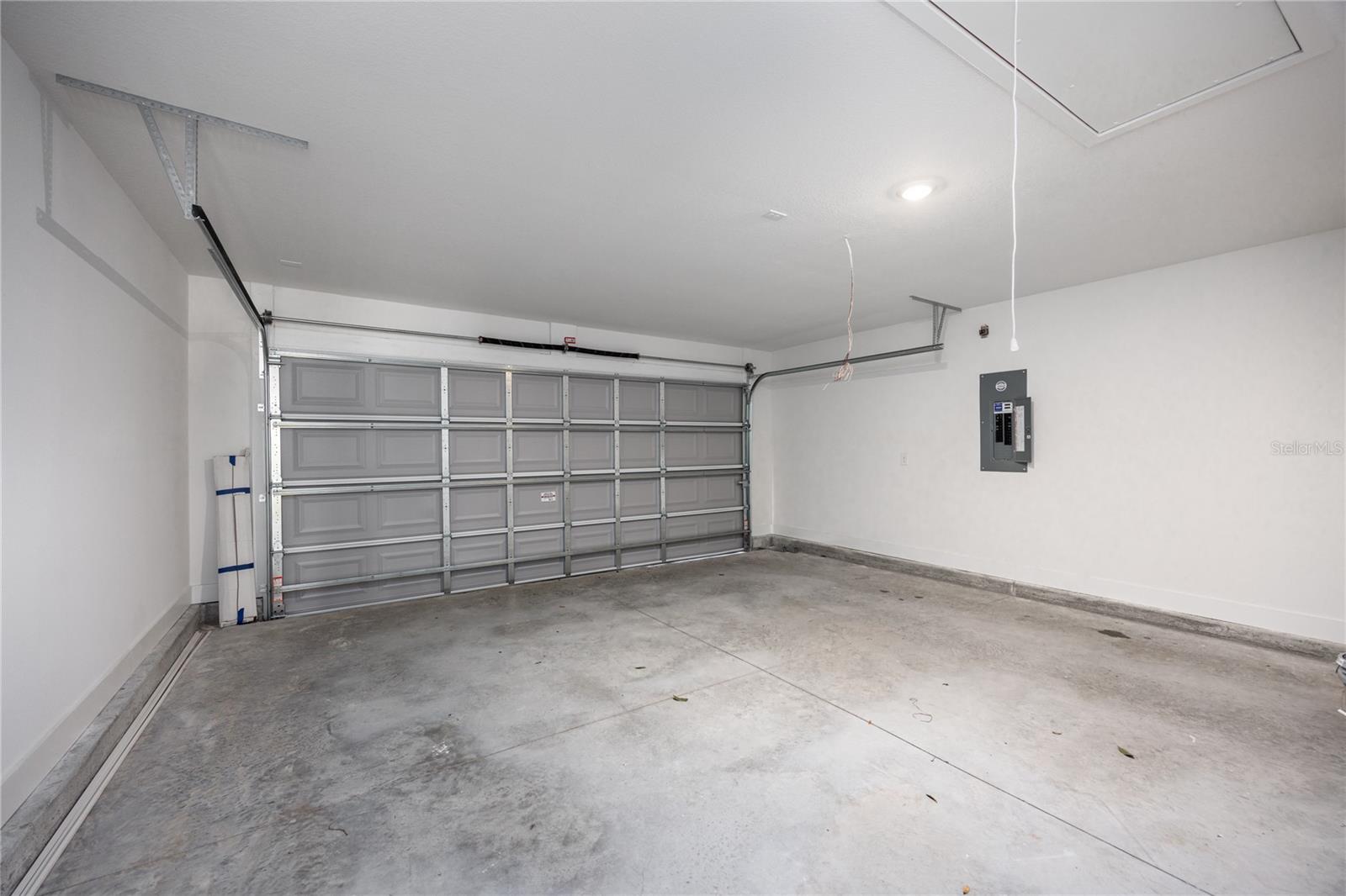 A clean, empty garage with white walls and a grey sectional garage door.
