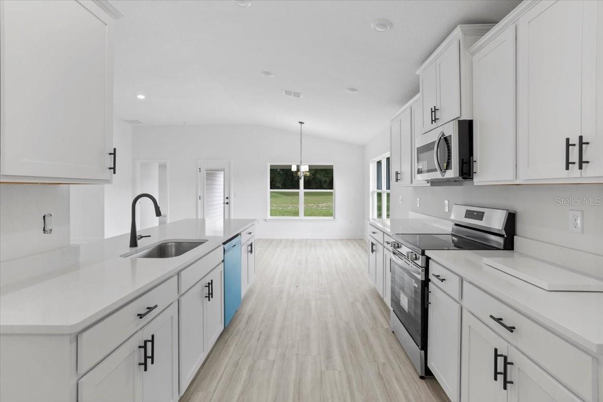 A bright white kitchen with stainless steel appliances and a unique blue dishwasher