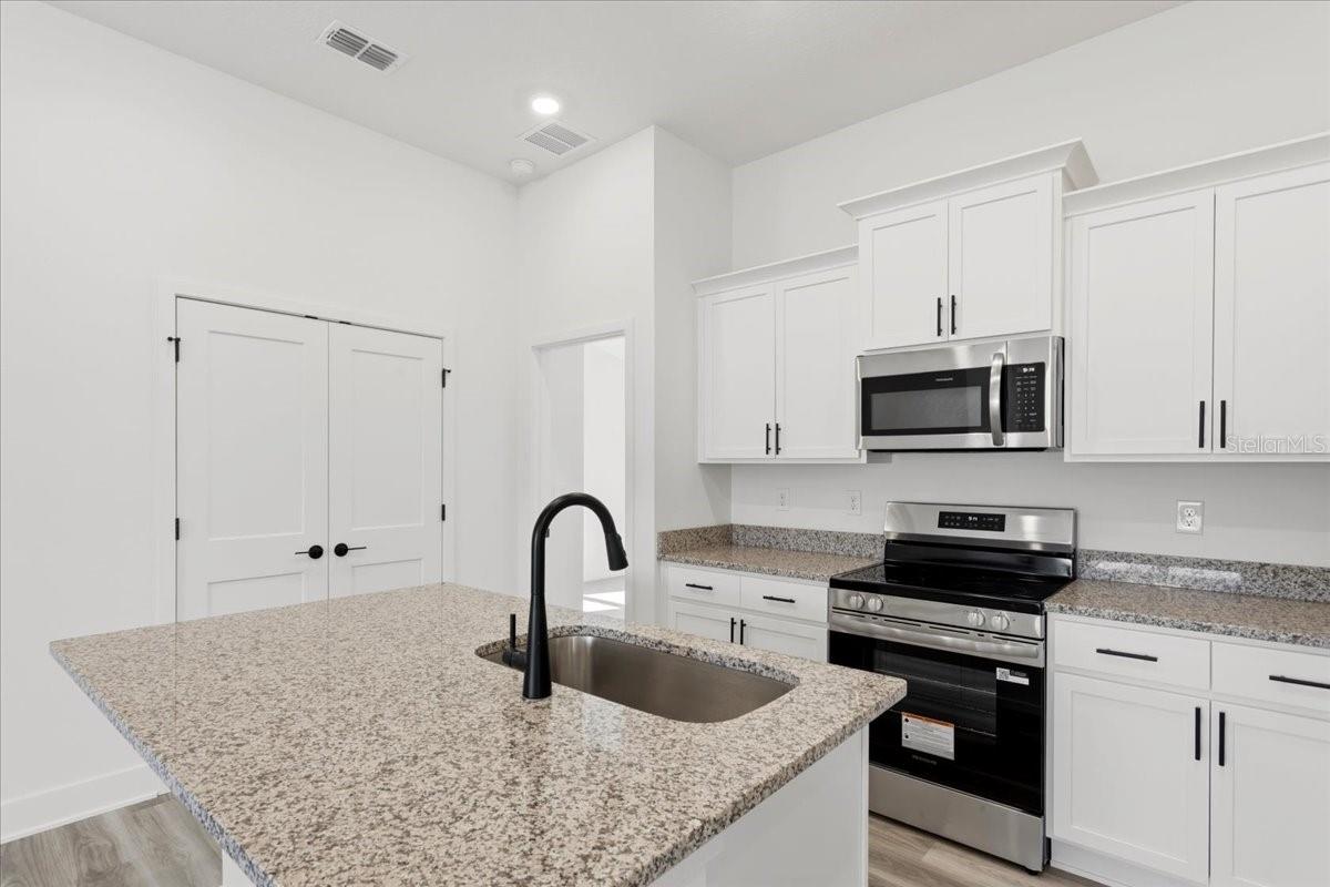 Modern kitchen with white cabinets, granite countertops, and black fixtures