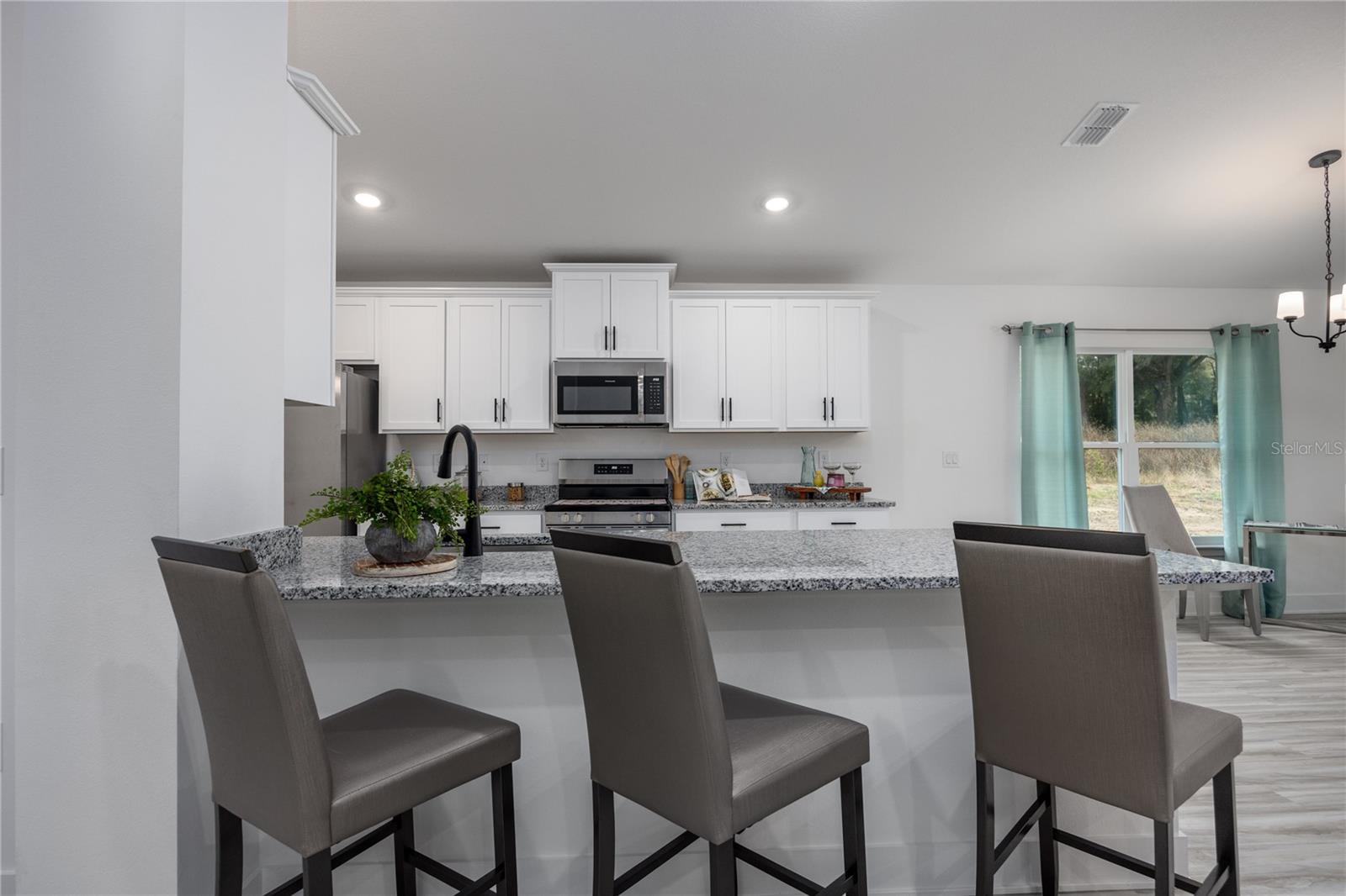Modern kitchen with white cabinetry, granite countertops, and breakfast bar seating