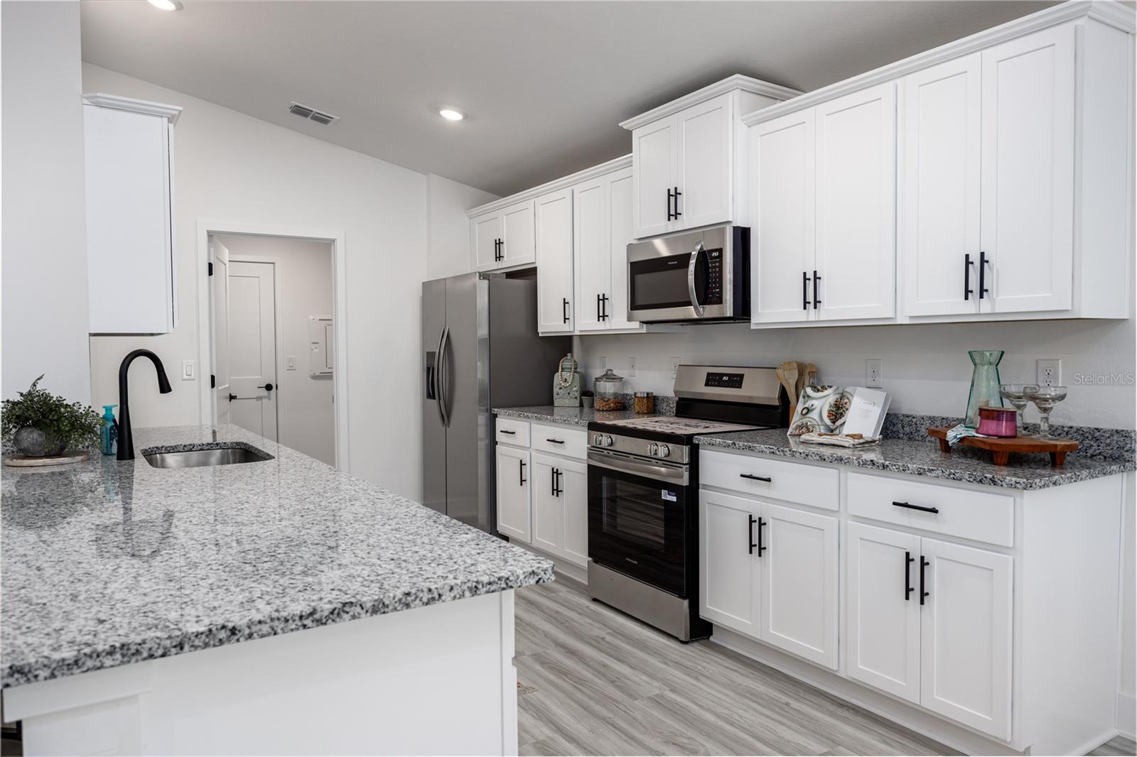 A modern, bright kitchen with white cabinets, granite countertops, and stainless steel appliances.