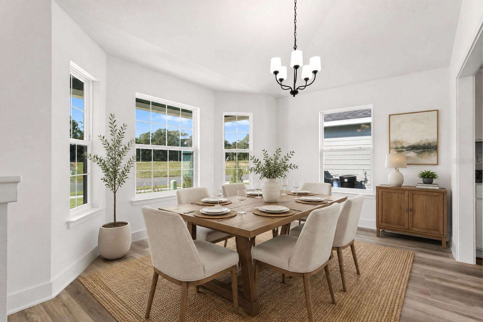 Bright, modern dining room with wooden table, six chairs, jute rug, and chandelier