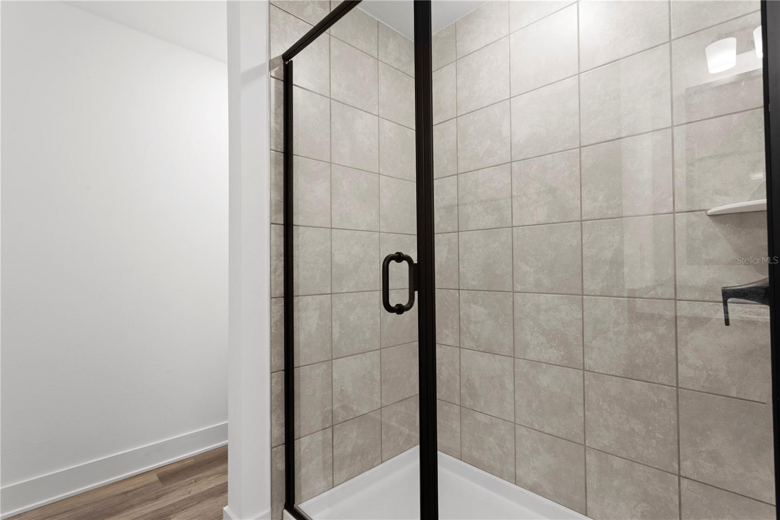 A tiled walk-in shower with a black frame glass door.