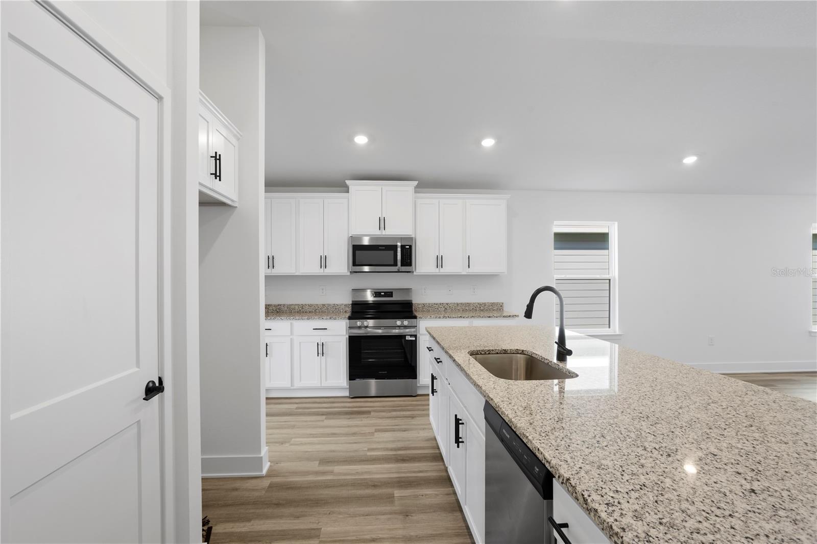 Modern kitchen with white shaker cabinets, granite countertops, and stainless steel appliances