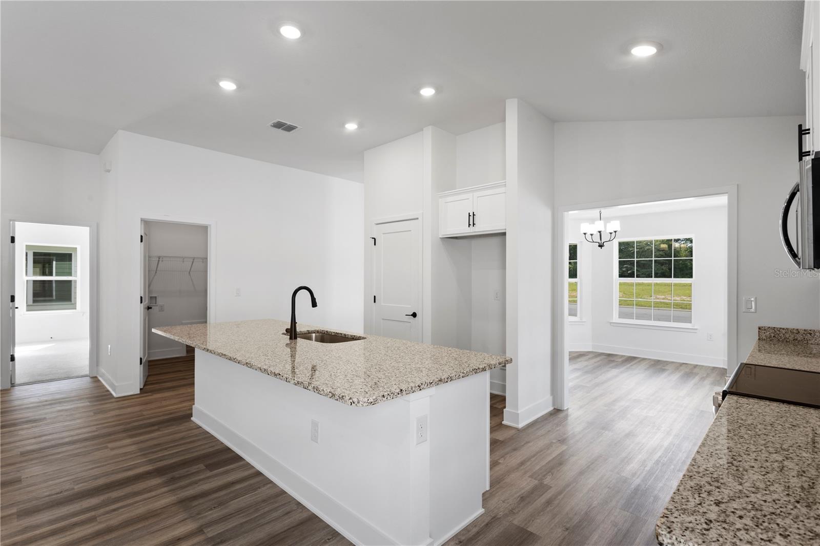 Modern white kitchen with granite countertops and kitchen island in an open floor plan