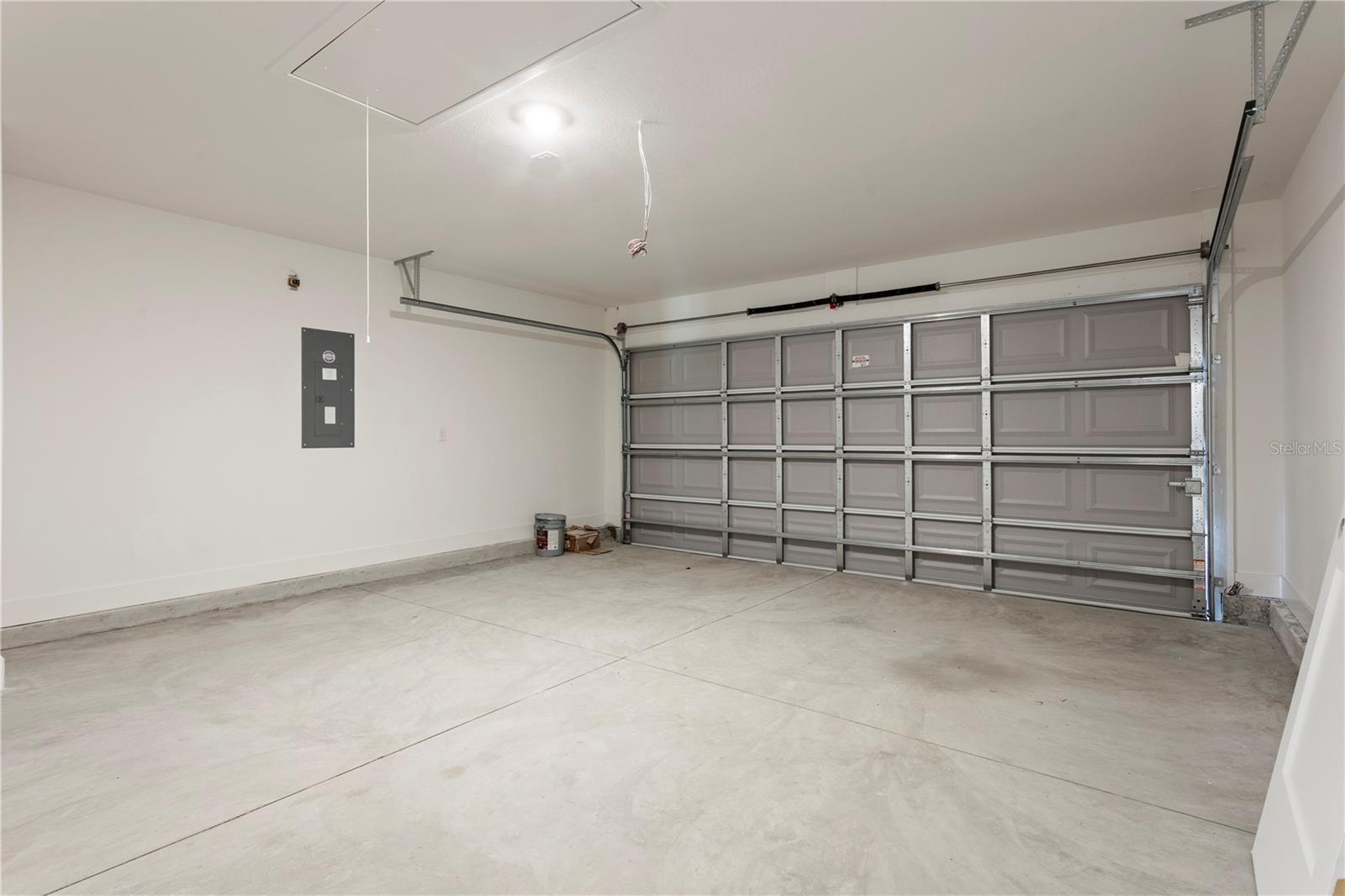 A standard two car garage interior with gray sectional door and concrete flooring