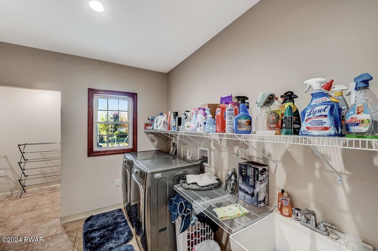 Laundry room with washer and dryer, wire shelving lined with cleaning supplies, a utility sink, and a window.