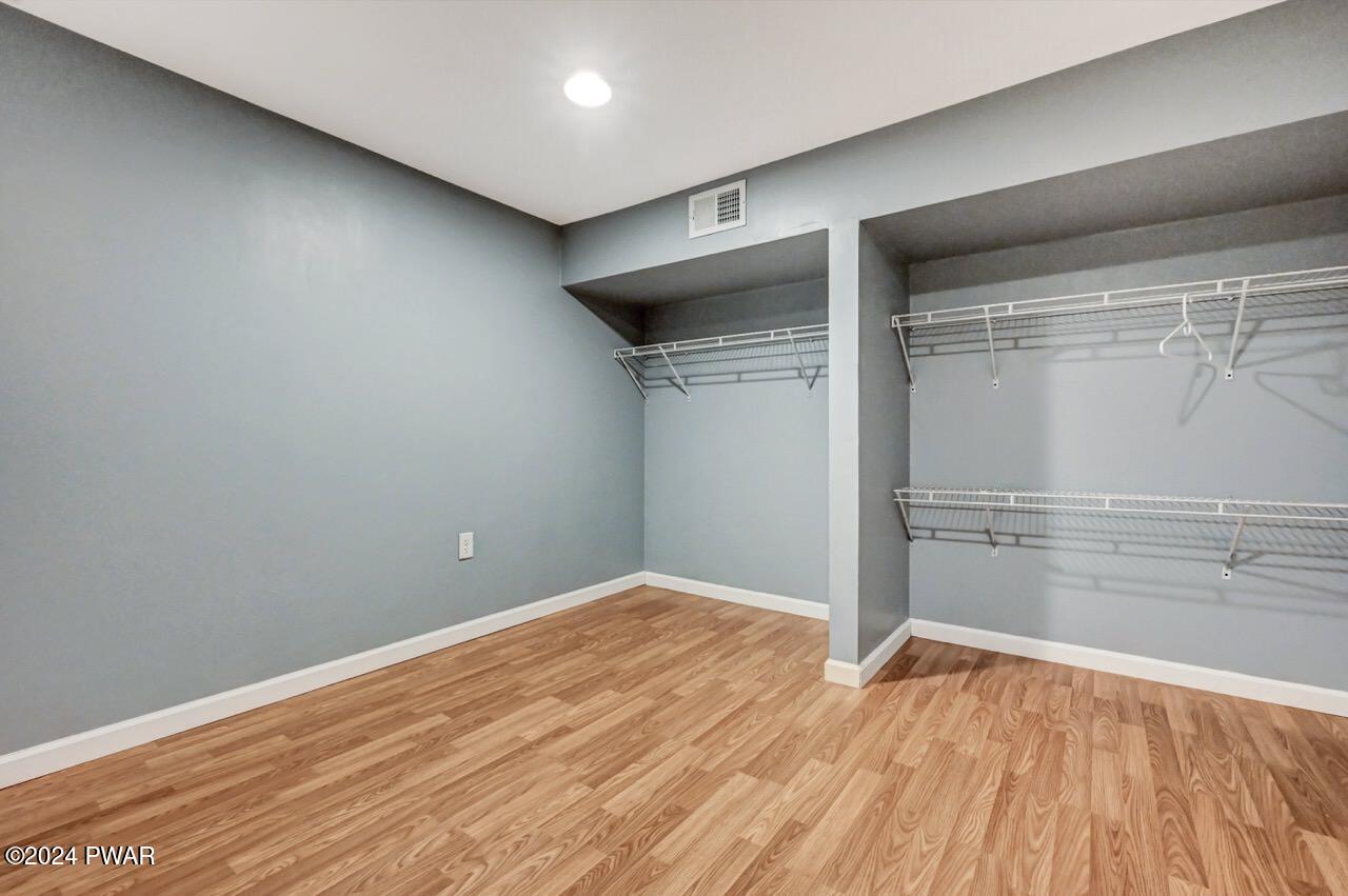 Empty walk-in closet with gray walls, white wire shelving, and wood-look flooring.