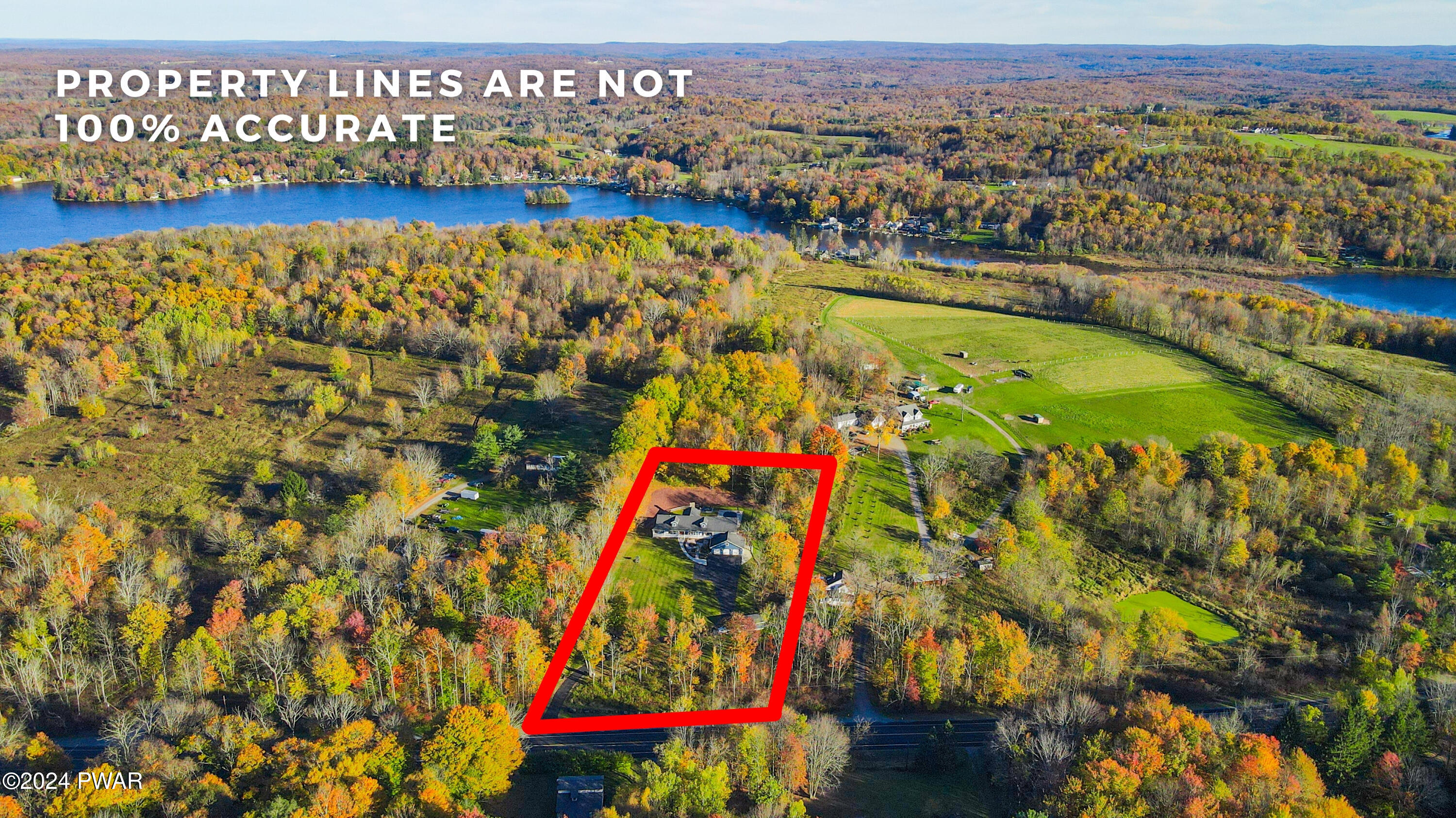 Aerial view of a rural property outlined in red near lakes, fields, and wooded land, with a property-lines disclaimer overlay.