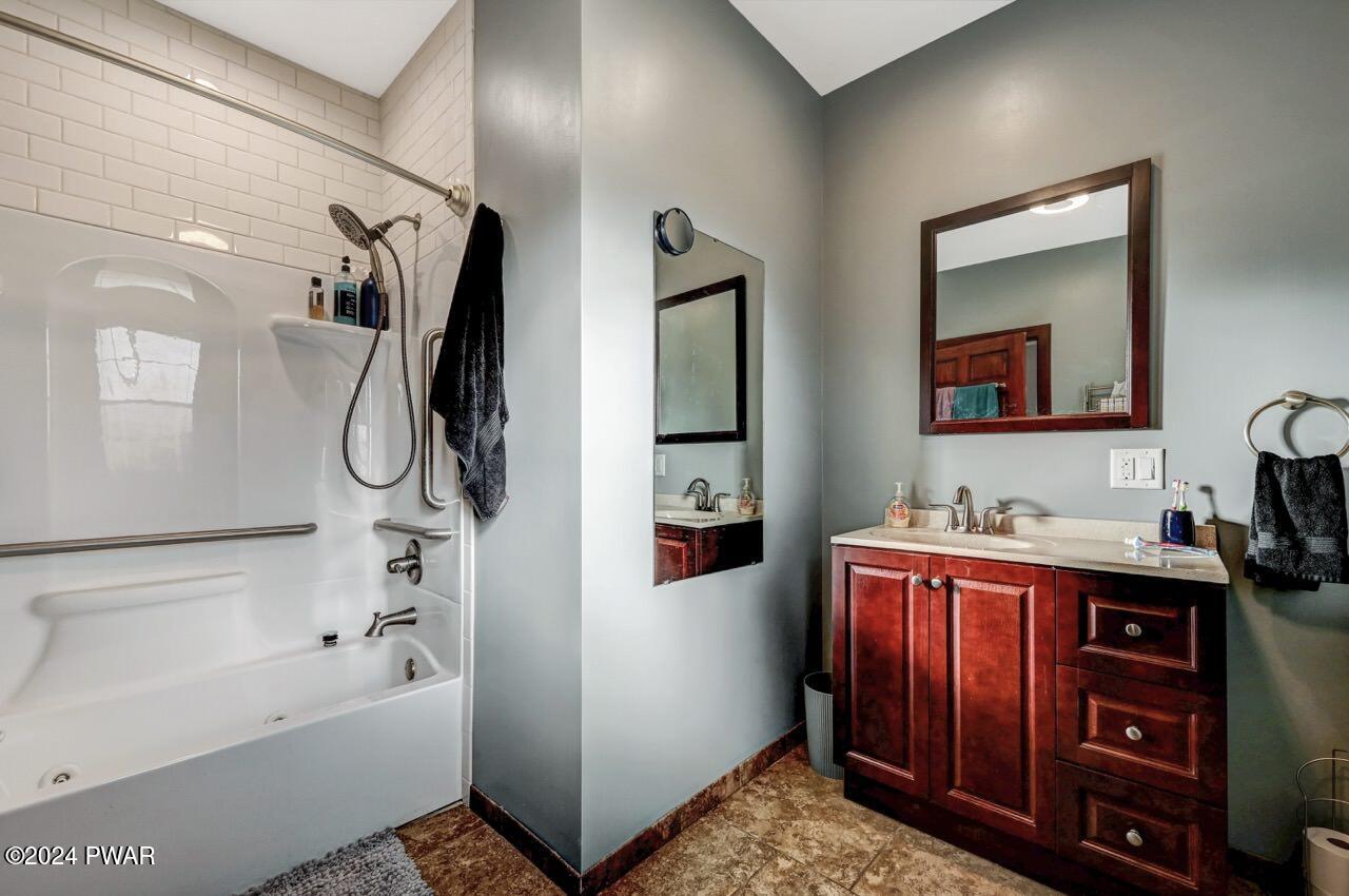 Bathroom with a tub-shower combination on the left and a dark wood vanity with sink and mirror on the right.
