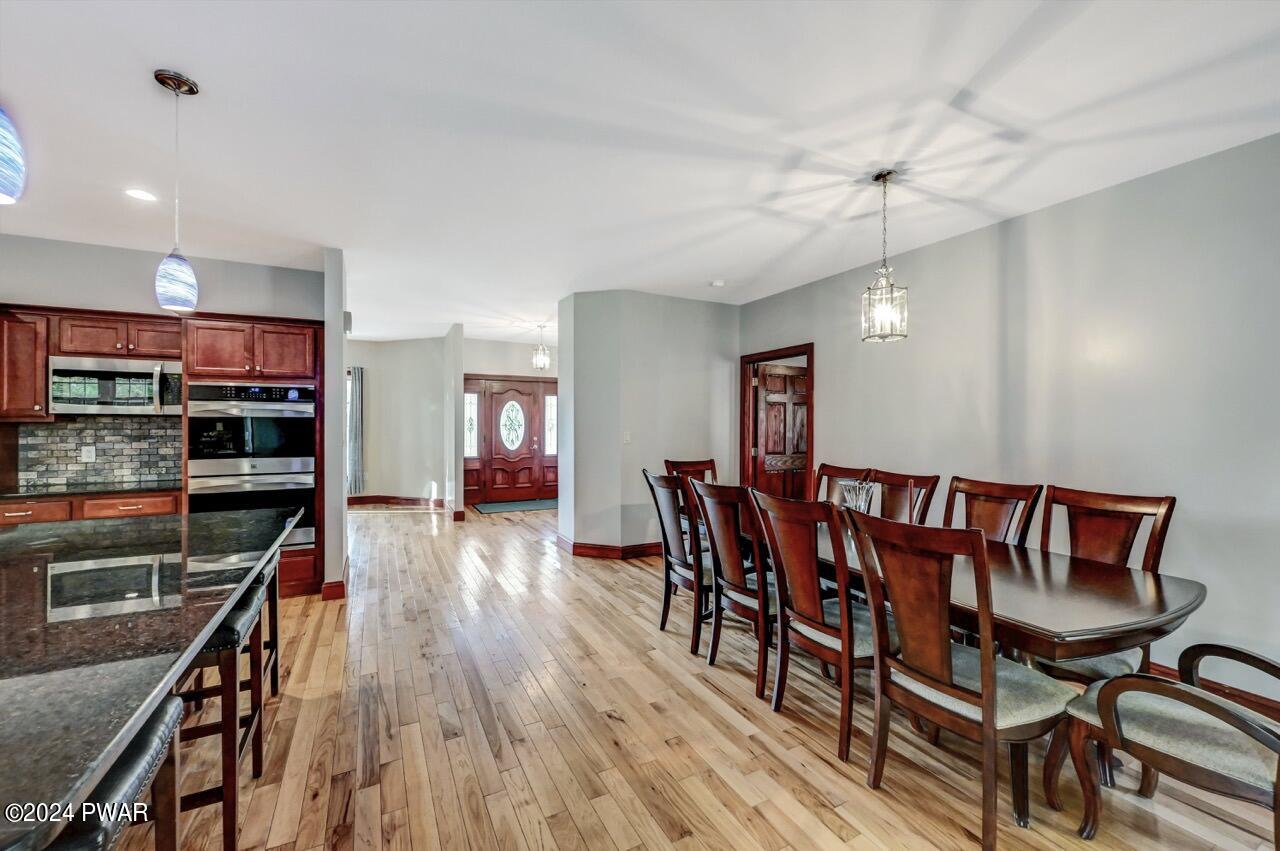 Bright open dining area beside a kitchen with wood cabinetry, hardwood floors, and a dining table with chairs near the wall.